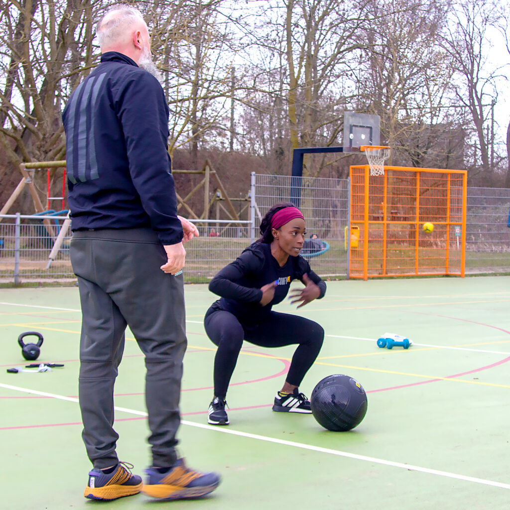 ComfyFit doet een oefening voor met een slamball tijdens een buiten sport small group training
